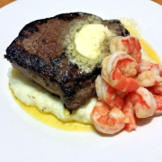 Pan-seared sirloin steak with garlic compound butter on top of Boursin mashed potatoes and garlic-infused butter shrimp